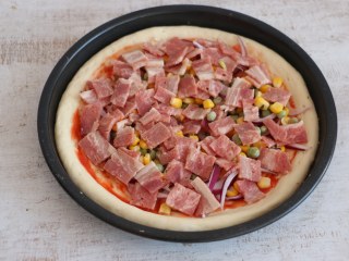 9、培根披萨,将配料均匀的撒在披萨饼底上。