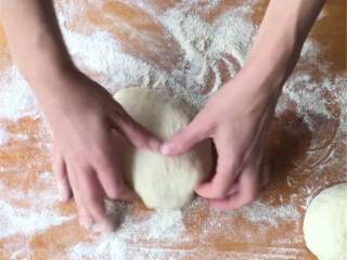 3、芝麻菜熏火腿披萨,把面团转移到撒了粉的工作台上，轻柔地整成球状，然后分成6份；一次取一份面团，迅速整成球状，再撒上面粉，放在工作台或者撒了粉的烤盘上，其余的面团也如此操作。