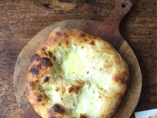 6、芝麻菜熏火腿披萨,准备烤的时候，先把面团擀开成直径25-28厘米的圆片，转移到垫了烘焙纸的烤盘上；抹上几汤匙的鲜奶油（适量），撒上新鲜马苏里拉芝士 。