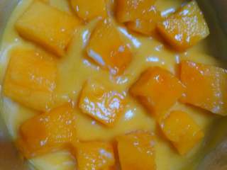 3、芒果流心慕斯,往蛋糕上倒一层慕斯糊，再摆上芒果丁