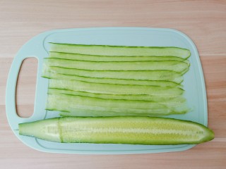 5、凉拌黄瓜卷,黄瓜对半切开，用削皮刀削成长长的薄片。
