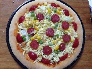 23、腊肠肉松披萨,最后在表面点缀小番茄、腊肠片、玉米粒、豌豆粒