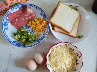 1、吐司培根披萨,准备食材备用，芝士碎提前解冻，玉米粒和青椒洗干净控干水分