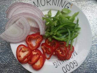 2、时蔬披萨,发面期间准备馅料。青椒红椒洗净、洋葱去皮洗净，分别切成丝，待用。马苏里拉奶酪提前从冷冻拿出来。