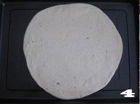4、【花边培根披萨】换着花样吃披萨,取2/3面团揉匀擀成圆形饼皮，放置在烤盘上。