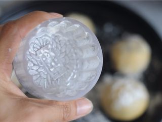 7、红豆月饼,模具里面撒些面粉,转圈,将面粉均匀粘在模具里,模具朝下,轻轻将多余的面粉磕出来