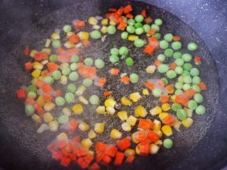 3、田园时蔬吐司披萨,锅中倒入适量的清水煮沸后，把玉米粒和胡萝卜丁，豌豆倒入锅中进行焯水，煮至1分钟左右捞出沥干水分。