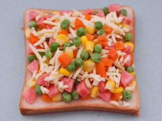 10、田园时蔬吐司披萨,我在芝士碎上又撒了一些时蔬碎，这样就可以让宝贝多吃一些蔬菜咯。