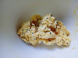 7、南瓜芝麻小饼干,加入黑芝麻，用筷子搅拌均匀，如图，再用手揉成面团。(低筋面粉可以实际情况增减，因为不同的面粉吸水量不同。)