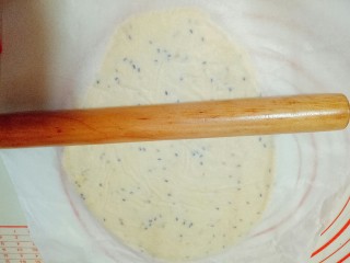 10、南瓜芝麻小饼干,把面团上面垫一张油纸，用擀面杖擀薄，约0.4cm的薄厚。