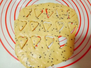 11、南瓜芝麻小饼干,面团擀好后，用磨具压出爱心形状，之后小心的取下爱心饼干，放入烤盘中，依次做完。