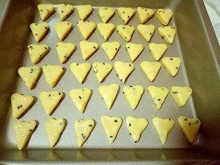 12、南瓜芝麻小饼干,全部做好的饼干整齐摆放在烤盘里，(我的是不粘烤盘，如果不是不粘的烤盘，需要垫上一张油纸，再把饼干放在铺有油纸的烤盘中。)