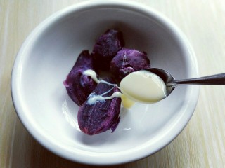 3、#感恩节食谱#南瓜紫薯馅饼,蒸熟的紫薯放入大口器具中，加入炼乳，用调羹碾压成泥。