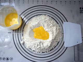 2、蔓越莓沙琪玛,面粉，泡打粉混合过筛到揉面垫上，然后中间挖空，倒入全蛋液。揉成湿润的面团，非常粘软的状态，据说这样做出来的沙琪玛才松软