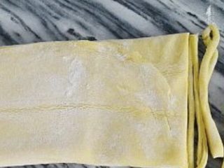 4、蔓越莓沙琪玛,在面团上撒上玉米淀粉防粘，然后擀成0.2厘米厚的薄片。用披萨轮刀切成细坯条，在皮条上撒上玉米淀粉防粘