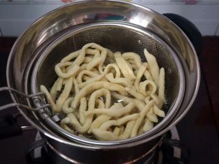 6、蔓越莓沙琪玛,将一条坯条放入油锅试油温，若坯条迅速浮起涨大表示油温可以，开始放入坯条，炸坯条