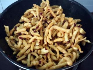 9、蔓越莓沙琪玛,熄火，倒入炸好的坯条和蔓越莓干，趁热快速翻拌，让每一根坯条都能沾到糖浆