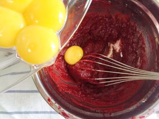 6、覆盆子红丝绒蛋糕,搅拌到无干粉状态就可以逐个加入蛋黄，每加入一个蛋黄都要搅拌均匀再加下一个。直到完全搅拌均匀，面糊呈缓慢滴落状态，将面糊盖保鲜膜待用。无需冷藏，常温即可。