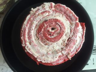 23、覆盆子红丝绒蛋糕,下面我用披萨盘做底盘，将抹好奶油的蛋糕依次卷成卷，两片之间做到头尾相连，6寸蛋糕我共用了4片蛋糕片卷，剩下两片刚好做了一个4寸的迷你蛋糕，四片蛋糕片最后卷成了一个圆柱形，包保鲜膜放冰箱冷藏定型