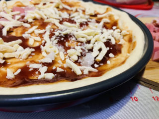 23、培根火腿披萨,披萨皮涂上披萨酱，撒上芝士碎