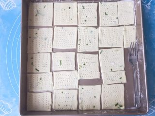 11、香葱味苏打饼干,把饼干转移到烤盘上，用叉子扎出小孔（防止烘烤时饼干鼓起不平整）