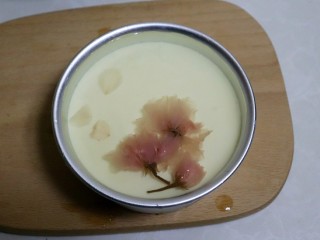 14、樱花芝士慕斯,把剩余的吉利丁液放入少许细砂糖（可免）微微加热至糖融化，晾到室温，倒入模具表面，放上几朵樱花装饰。