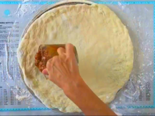 3、车打芝士披萨【披萨的做法】,把辣椒酱倒在胚底上面。