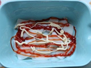 6、芝士焗年糕,年糕铺在底部。挤上沙拉酱，番茄酱