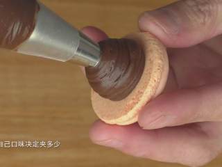 96、超详细马卡龙教程,取一个饼身，挤上夹馅，我用的巧克力甘纳许夹馅，具体的做法请看我另外一个视频；