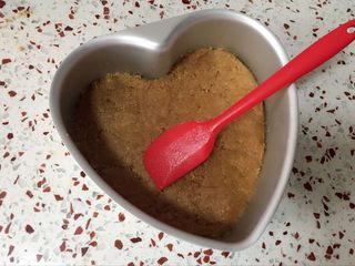 4、心形火龙果慕斯,将混合好的消化饼干铺在蛋糕模的底部,压紧后放入冰箱冷藏半小时.