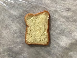 5、纸盒三明治,在保鲜膜的中间位置放上一片吐司，并且均匀抹上适量沙拉酱