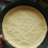 3、水果披萨,用擀面杖把面饼擀成与披萨烤盘一样大，然后把面饼放入到烤盘，用叉子扎很多气孔。