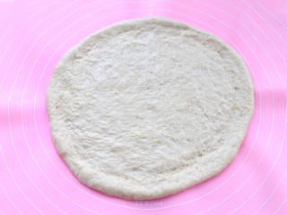 3、香蕉芒果披萨——九寸,将面团取出揉匀排气后，覆盖保鲜膜松弛20分钟，然后用擀面杖擀成中间薄边缘厚的饼皮