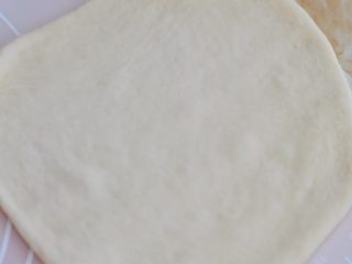 7、花朵紫薯面包,取一个面团，擀薄擀大，尽量擀圆。