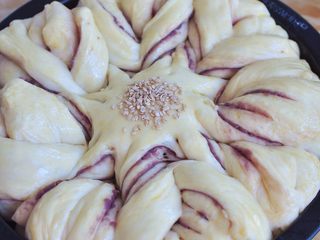 13、花朵紫薯面包,面团发酵至满模后，表面刷一层蛋液，中间处撒上白芝麻。放入烤箱中，170度烘烤20分钟。