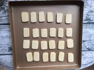 12、炼乳小饼干（适合新手）,冻硬后取出切成厚度均匀的小片并均匀摆入烤盘，不要冻得太硬以免切碎，我用的是不粘烤盘，其它烤盘最好垫一层烘焙纸