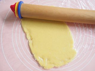 7、巧克力脆棒,盖上一层保鲜膜，擀成薄片，将面片对折后再擀开，重复3~4次。