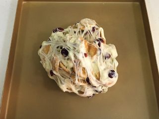 9、坚果雪花酥,把雪花酥团倒入不粘烤盘内，用双手不停往外翻，直到饼干和坚果料都被千丝万缕的糖包裹住。