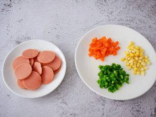 2、杂蔬火腿肠披萨,把玉米粒洗净备用，胡萝卜去皮洗净切丁，青椒洗净切丁，火腿肠切片备用