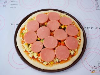 9、杂蔬火腿肠披萨,再放入胡萝卜、玉米粒、青椒、火腿片