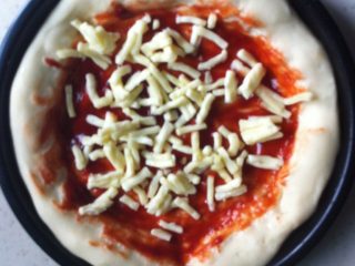 11、披萨,铺上一层马苏,接着把香肠切处,培根切片,按顺序铺均匀铺上.