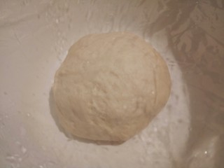 8、自制火腿肠披萨,发酵好的面团给它稍微排一下气,再盖保鲜膜醒发10分钟,(排气的时候你会听见噗噗噗的声音,就是小泡泡揉破的声音,)排好气了,可以把烤箱预热,200度,预热10分钟