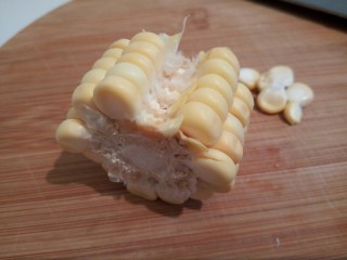 9、自制火腿肠披萨,趁着面团醒发的时间我们来准备馅料,玉米给它切成这样的小段,中间一排,先用刀给挖下来,