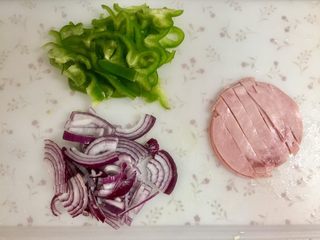 2、快手鸡蛋火腿飞饼披萨,青椒、洋葱洗净，切丝，火腿片切成条，用火腿肠切成片亦可。