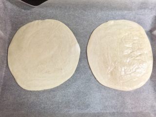 4、快手鸡蛋火腿飞饼披萨,烤盘上铺烘焙纸，把飞饼皮拿出冰箱，放在烘焙纸上，无需提前解冻。烤箱可以开始预热，200度。