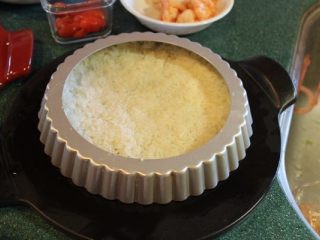 7、香甜米飯+米披萨,将米饭放入倒扣的派模，用手将饭铺平压紧。手沾一些水，手指就不会沾黏饭粒。