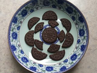 12、奥利奥巧克力香蕉派(免烤),12.奥利奥饼干中的夹心去掉,分成大小不同的块,在盘子里模拟摆放一下自己想要的图案。
