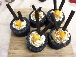 19、奶油黑杯子,插上两根巧克力棒,撒可可薄脆片,放芒果肉,装饰完毕