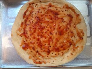 4、黑椒虾仁披萨,在烤盘刷一层油然后平铺面饼,用叉子扎眼,抹好披萨酱,披萨酱是用番茄酱黑胡椒粉盐糖混合烤一分钟制成的