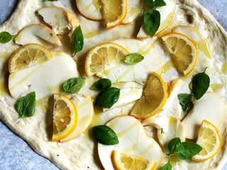 2、烟熏意大利干酪柠檬披萨,揉搓新鲜披萨面团(8盎司)，在面团上撒上面粉。与此同时，把柠檬片放水里浸泡15分钟，拍干。取出片状烟熏马苏里拉奶酪(3盎司)。